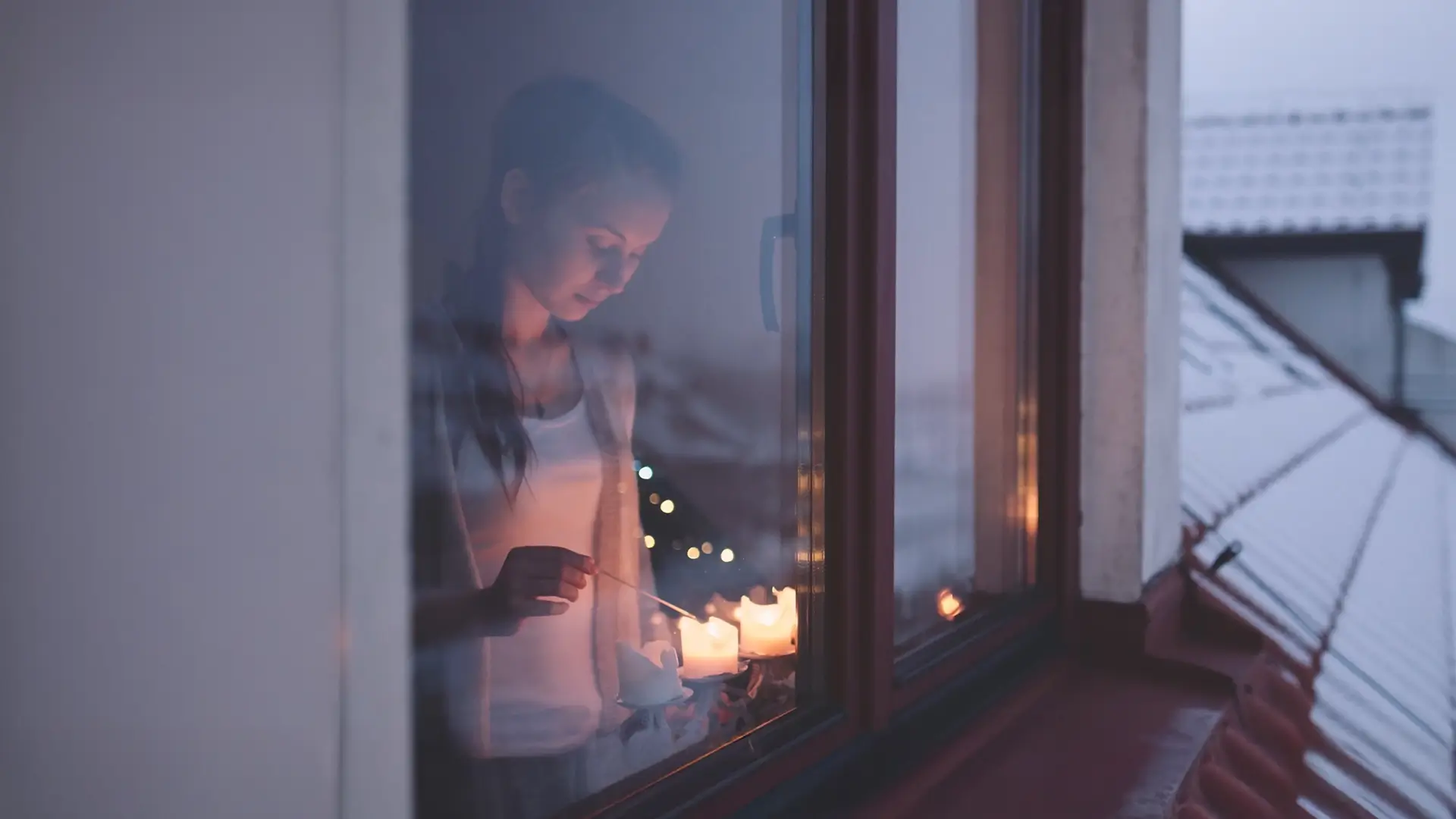 Woman standing in the window lighting candles